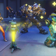Tracer, Mei, and Torbjorn stand and point their weapons ahead.